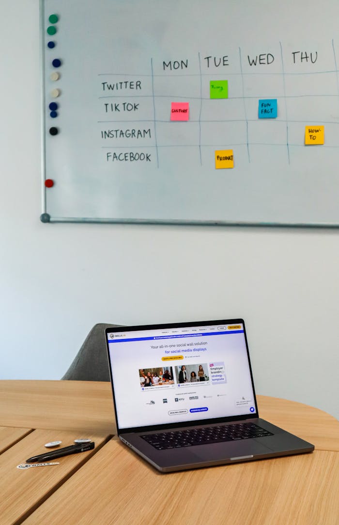 about-us A modern office setup featuring a laptop and a whiteboard schedule for social media platforms.